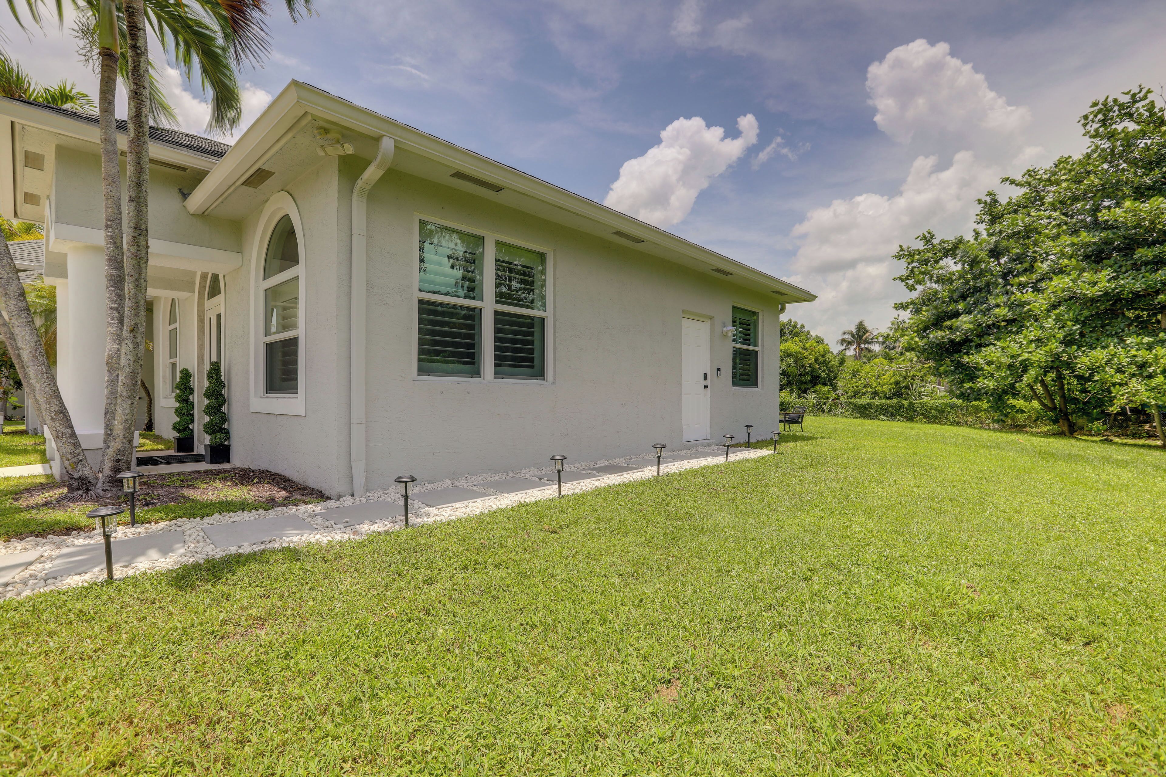 A single-story house with a flat roof, a covered porch, and a well-maintained lawn.