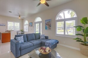 A living room with a blue sofa, a glass coffee table, and a large window with a view of the outside.