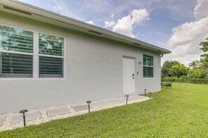 A single-story house with a white exterior, a front door, and a window with blinds.
