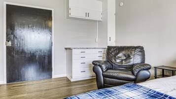 A room with a bed, a leather chair, a white cabinet, and a door.