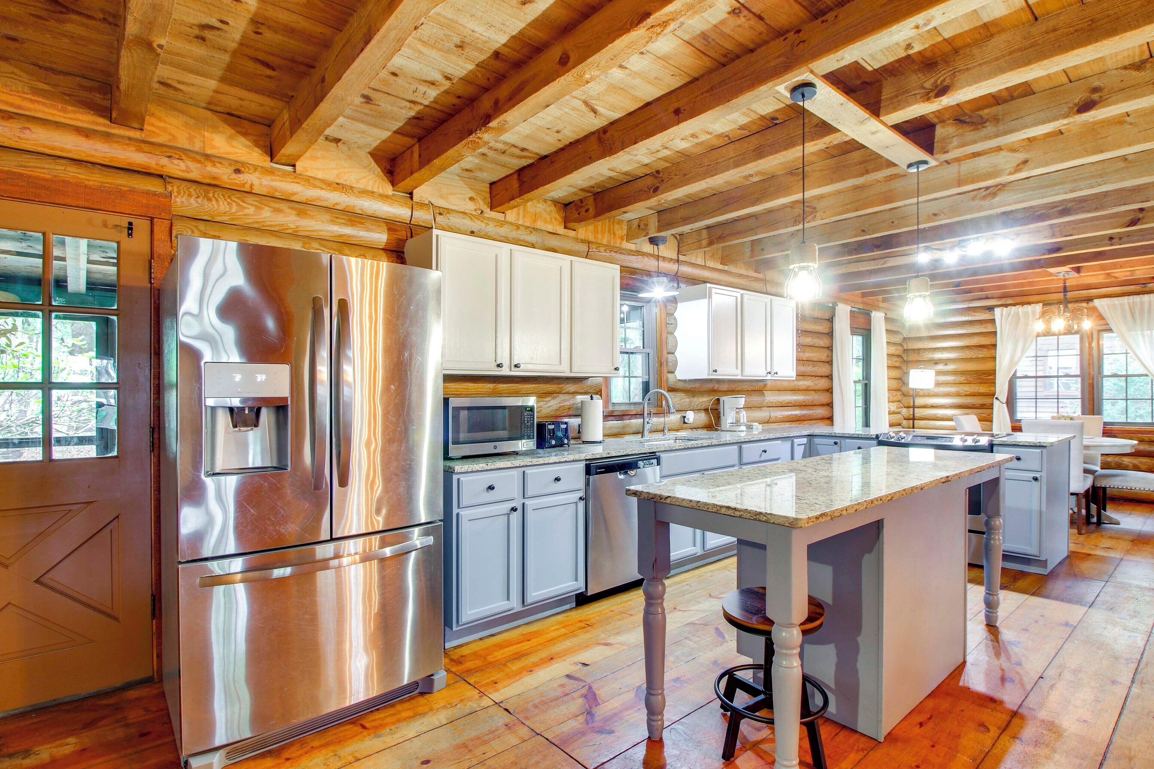 A modern kitchen with stainless steel appliances, white cabinets, and a central island with stools.