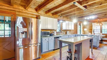 A modern kitchen with stainless steel appliances, white cabinets, and a central island with stools.