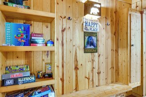 Ein Holzblockhaus-Interieur mit Regalen voller Gesellschaftsspiele und einem Willkommensschild.
