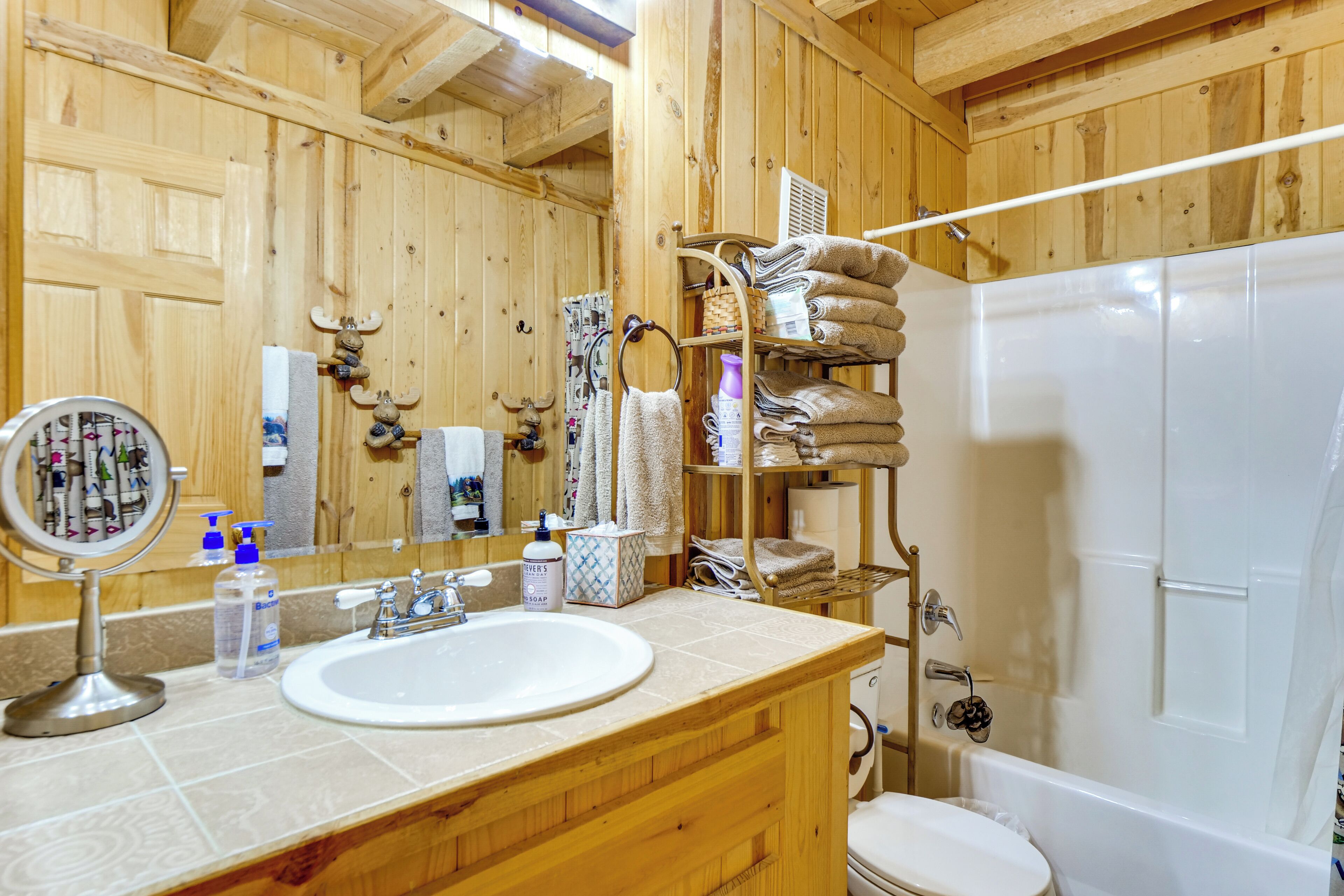 Ein Badezimmer aus Holz mit Waschbecken, Spiegel und Dusche.