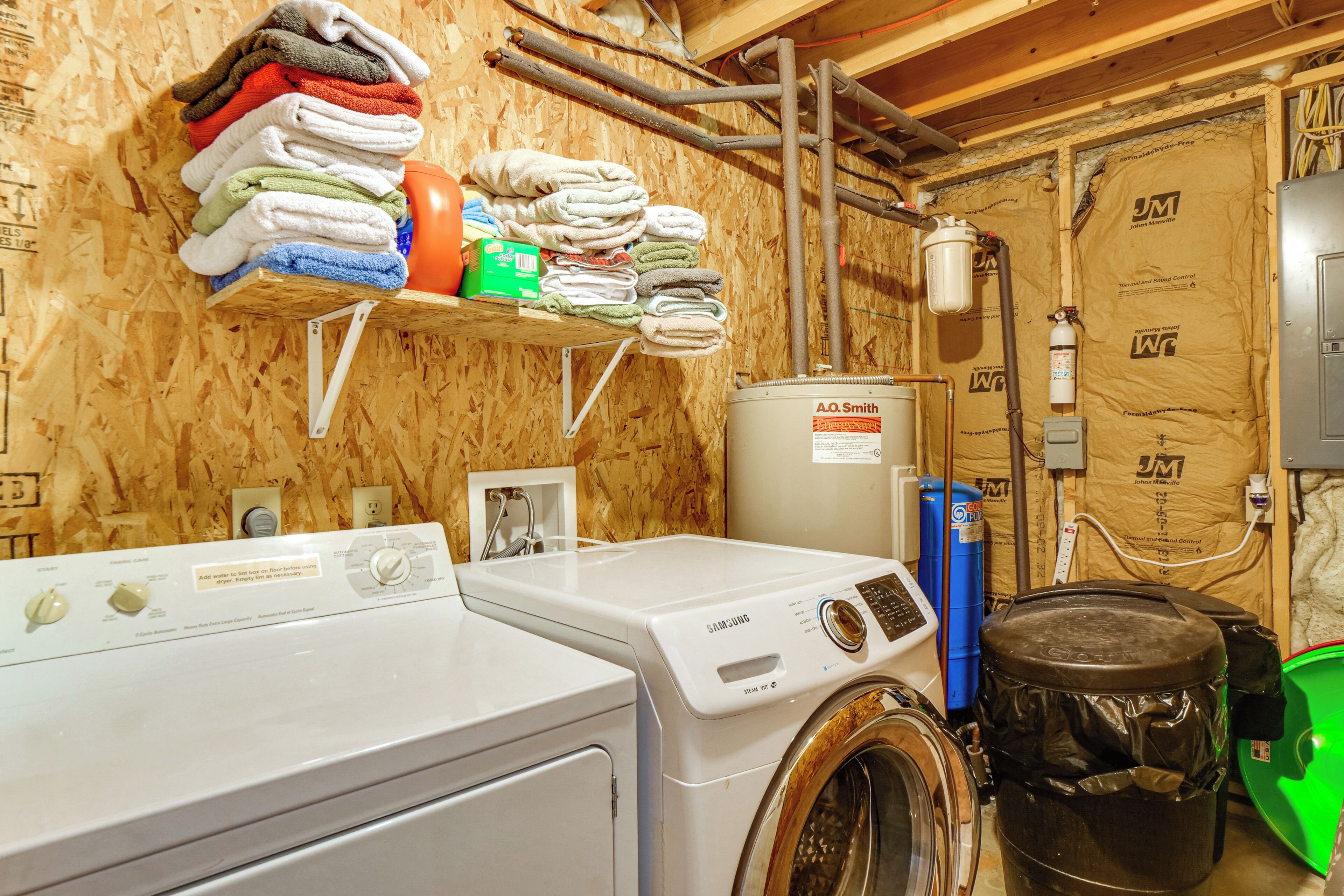 A laundry area with stacked towels, a washing machine, and a water heater.