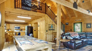 A spacious wooden cabin interior with a dining area, kitchen, and a leather couch. - Pool Table & Peaceful Porch: Fairplay Retreat (Fairplay)