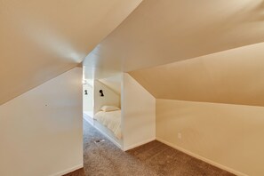 A bedroom with a sloped ceiling, a bed, and a carpeted floor.