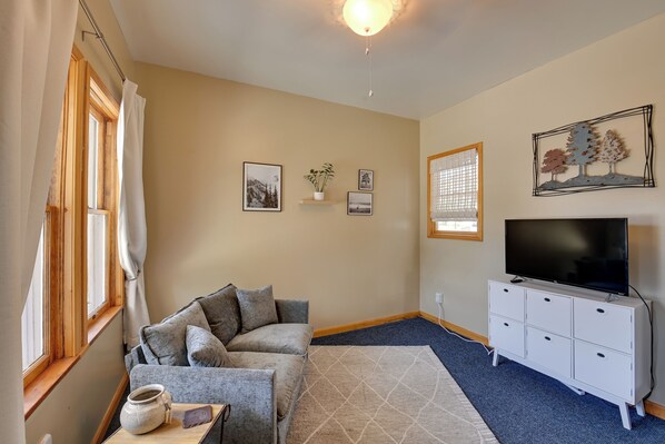 A living room with a sofa, a television, a cabinet, and a window with curtains.