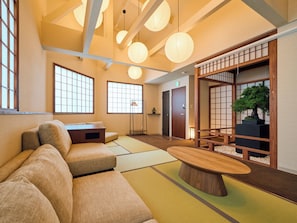 A traditional Japanese-style room with tatami flooring, a low wooden table, and a bonsai tree.