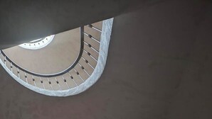 En svängd trappa med ett räcke och balustrader, som leder upp till en rund balkong med utsikt över himlen.