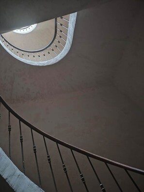 A curved staircase with a handrail and balusters, leading to a circular balcony with a view of the sky. - Omnia. Air conditioned charm in historic Frejus. (Fréjus)