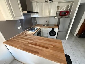 A modern kitchen with a wooden countertop, stainless steel appliances, and white cabinetry. - Omnia. Air conditioned charm in historic Frejus. (Fréjus)