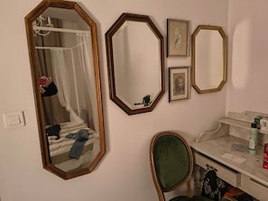 A room with a bed, a vanity with a mirror, and a chair. - Omnia. Air conditioned charm in historic Frejus. (Fréjus)
