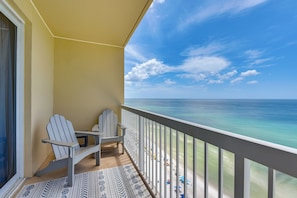 A balcony with two Adirondack chairs, a patterned rug, and a view of the ocean. - Beachfront PCB Condo: Walk to the Sand! (Panama City Beach)