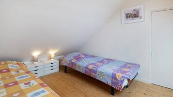 Ein Schlafzimmer mit einem Bett, einem Nachttisch, einer Lampe, einem Wandbild und Holzboden.