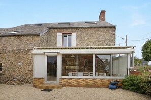 A stone building with a small attached structure featuring a door and windows.