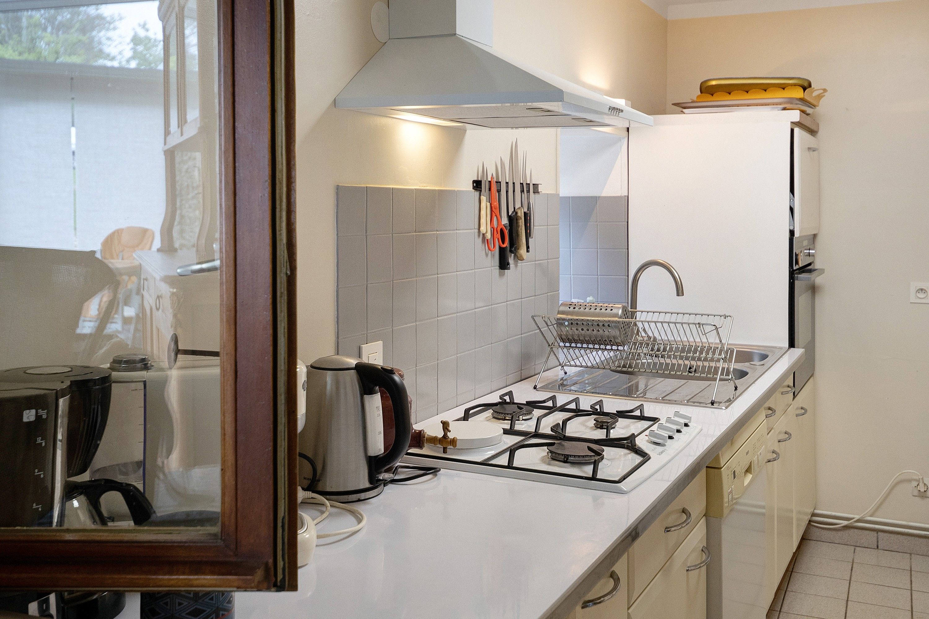 Une cuisine de taille réduite équipée d’une cuisinière à gaz, d’une bouilloire et d’un évier.