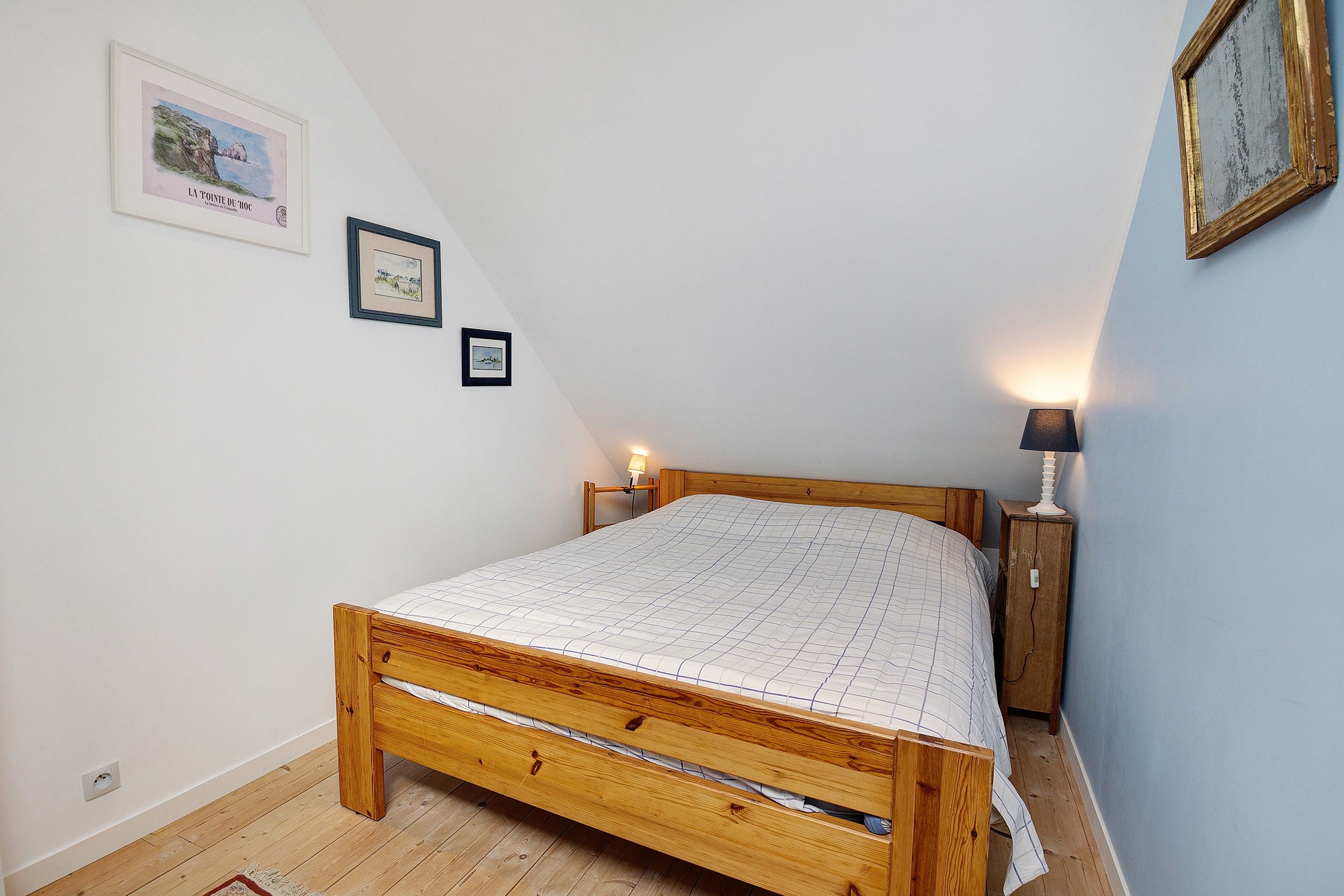 Un dormitorio con una cama de madera, dos mesitas de noche y lámparas de pared.