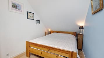 Un dormitorio con una cama de madera, dos mesitas de noche y lámparas de pared.