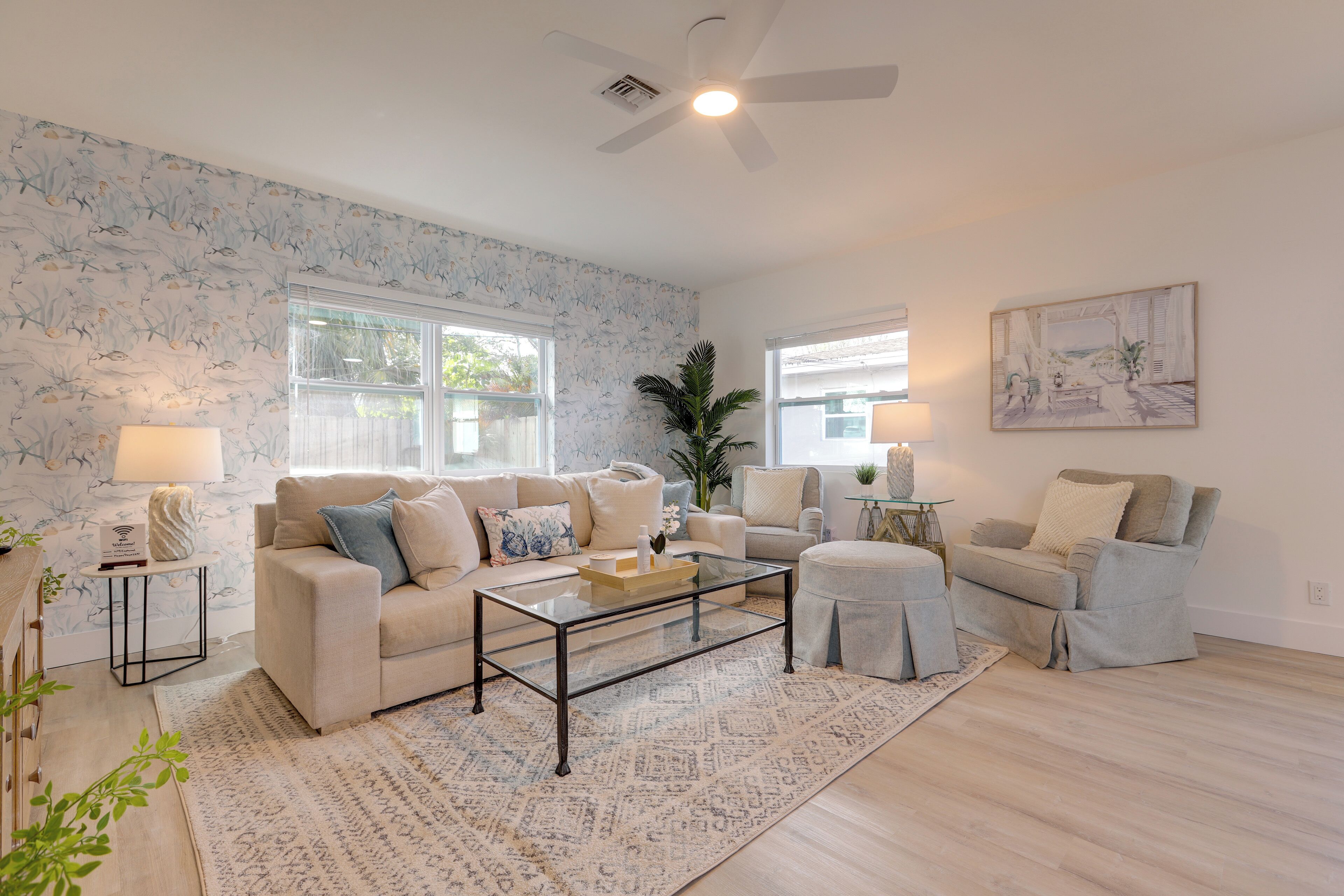 A living room with a sofa, armchair, coffee table, and a painting on the wall.