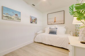 Ein Schlafzimmer mit einem Bett, weißen Wänden und drei Bildern.
