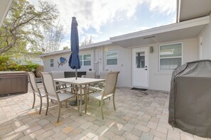 Eine Terrasse mit Tisch und Stühlen, einem überdachten Grill und einer überdachten Sitzgelegenheit.