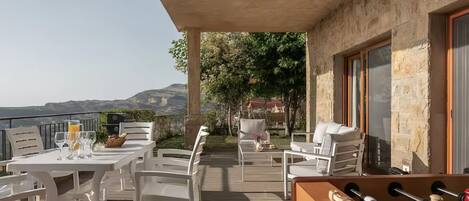 Un patio exterior con mobiliario blanco, mesa de fútbol de mesa y vistas al paisaje.
