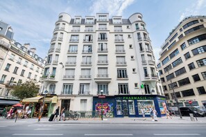 A multi-story building with a cafe and pharmacy on the ground floor. - Charming and Bright 1BDR Near the Marais (Paris)