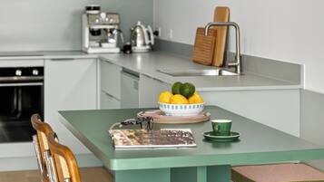 Eine moderne Küche mit einer zentralen Kochinsel, einer Kaffeemaschine und einer hängenden, orangefarbenen Pendelleuchte.