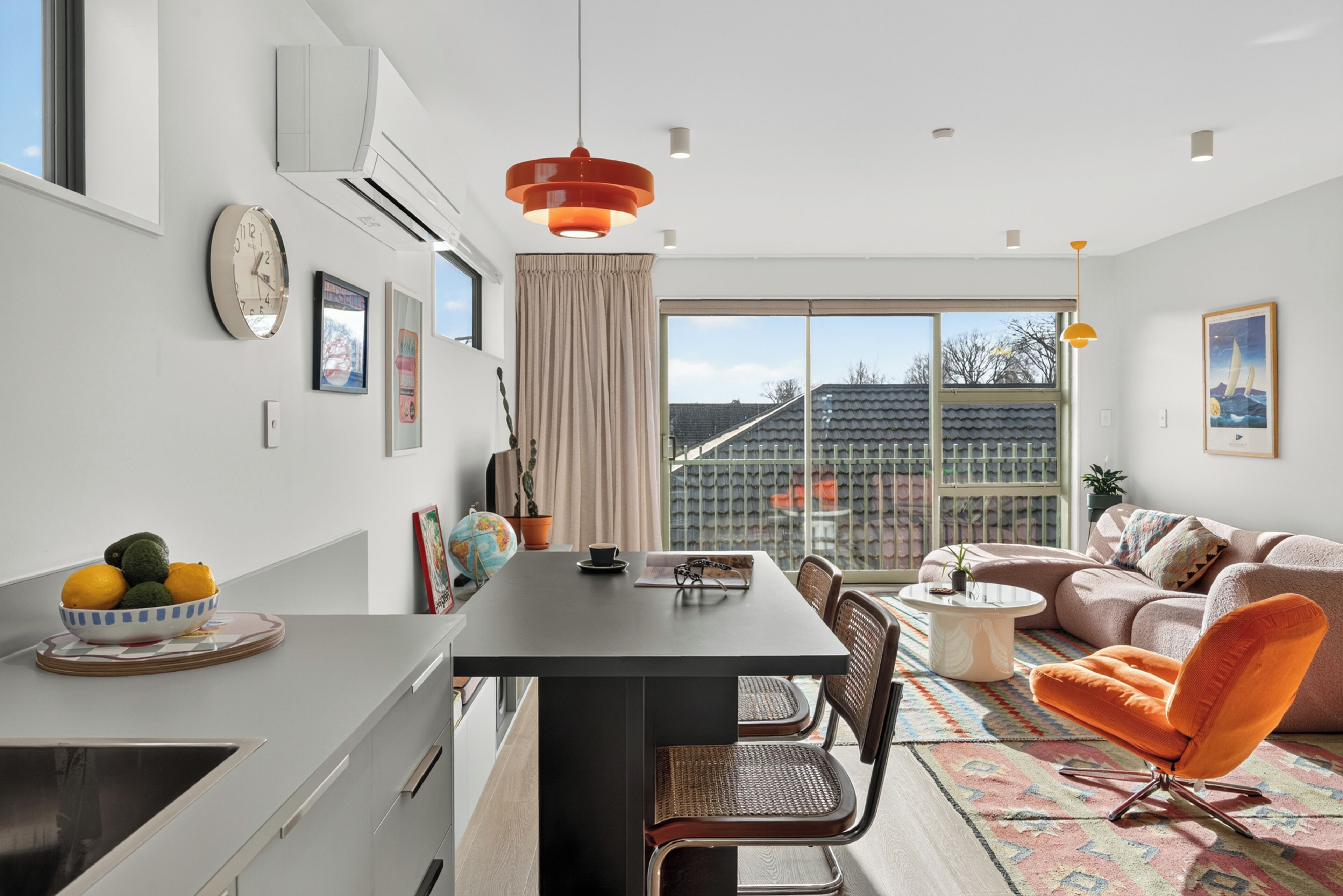 Ein modernes Wohnzimmer mit Essbereich, ausgestattet mit einer Couch, Sesseln, einem Couchtisch und einem Esstisch.