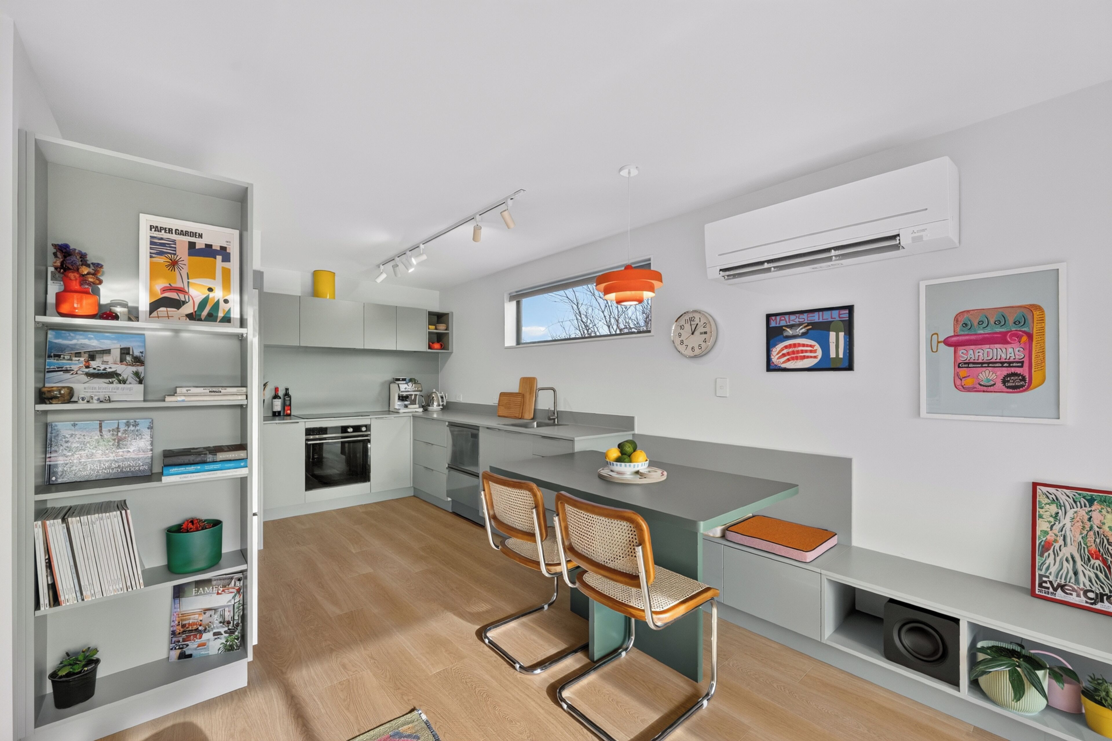 A modern kitchen with a central island, built-in appliances, and a dining area with two chairs.
