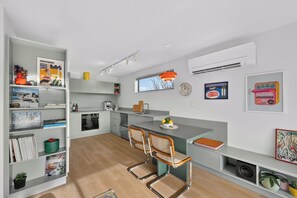 Una cocina moderna con una isla central, electrodomésticos integrados y un comedor con dos sillas.
