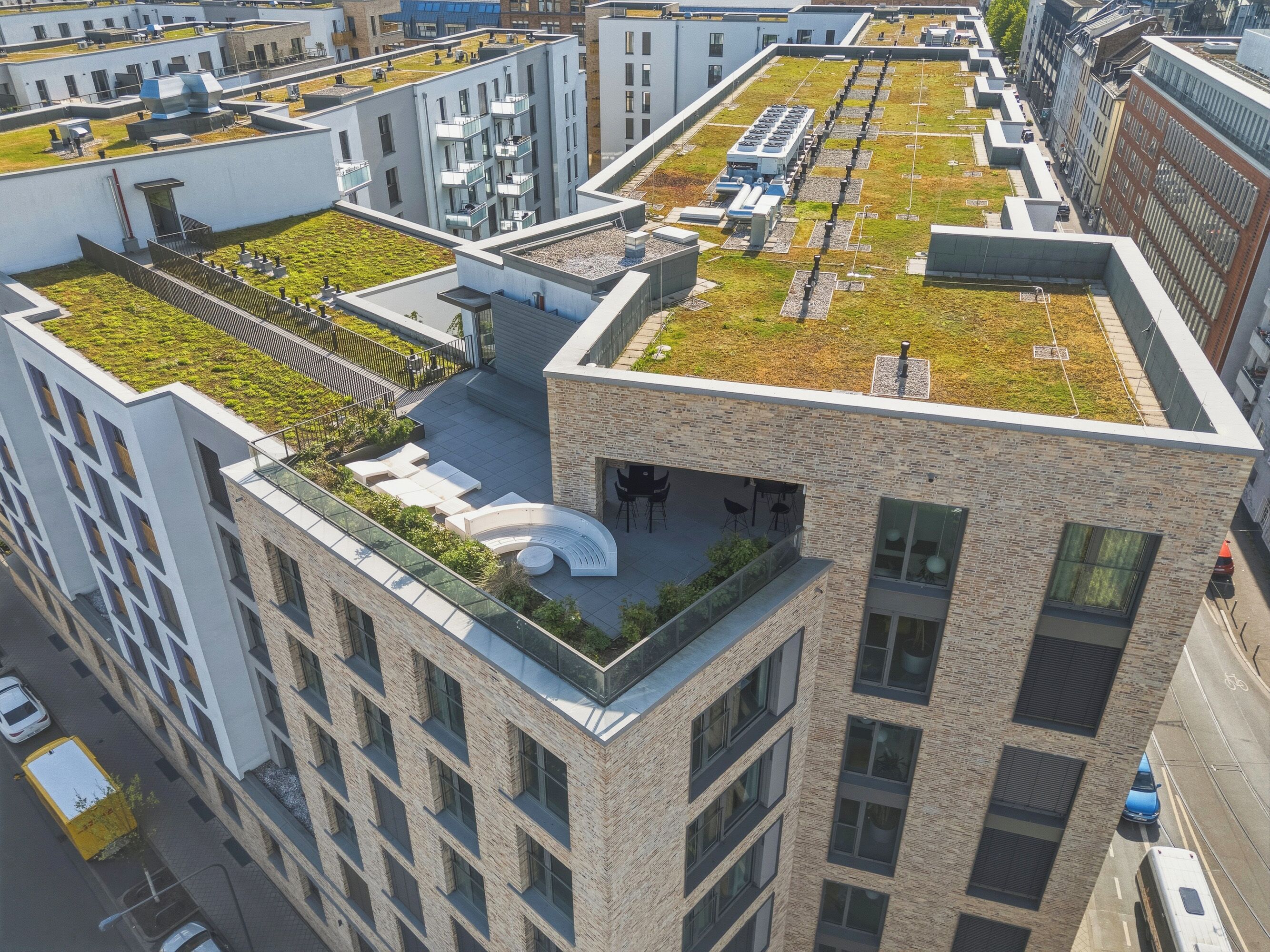 A modern building with a rooftop garden, multiple balconies, and a parking area.