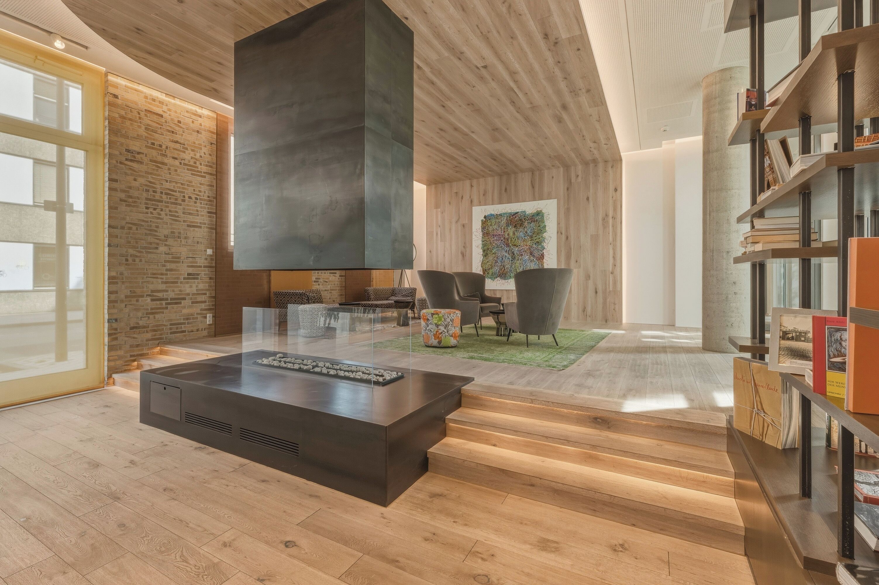 A modern living room with a fireplace, wooden flooring, and a bookshelf.