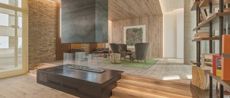 A modern living room with a fireplace, wooden flooring, and a bookshelf.