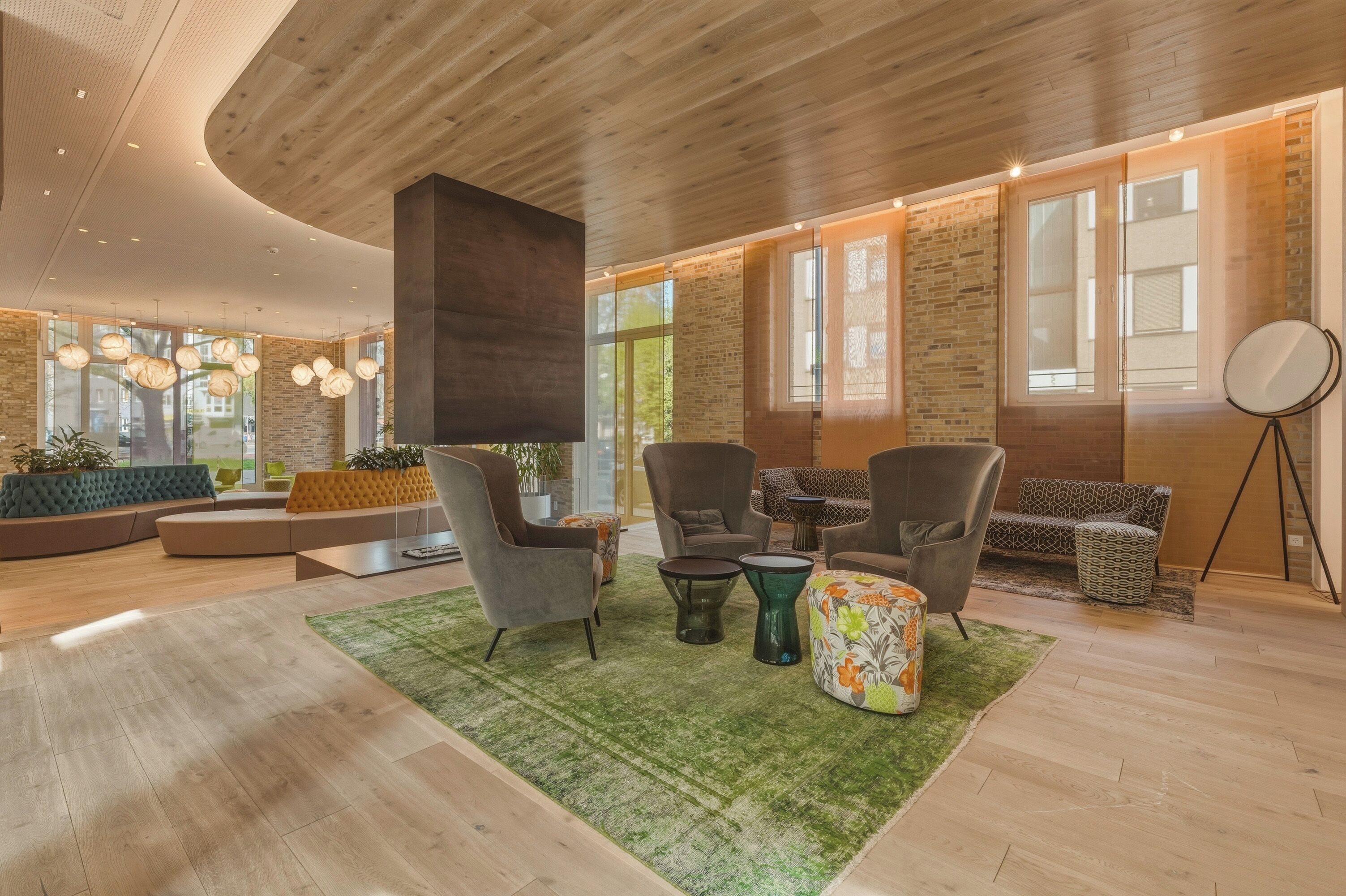 A modern interior with a wooden ceiling, large windows, and a mix of seating arrangements.