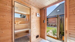 Et træbeklædt interiør med en skydedør, der fører til et udendørs område med en murstensvæg og udendørs møbler.