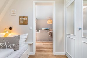 Ein Schlafzimmer mit einem Bett, einer Nachttischlampe, einem an der Wand befestigten Schild und einer Tür zu einem anderen Raum.