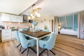 Eine moderne Küche mit weißen Schränken, einem Holzespeisetisch und blauen Stühlen.