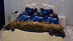 A bedroom with a white ornate bed, floral bedding, and a ceiling with blue lighting.