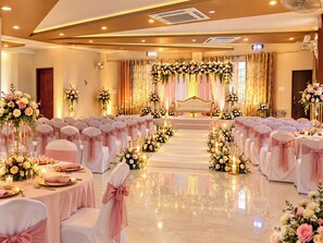 A wedding venue with rows of tables, chairs, and a stage with floral decorations. - THE VRINDAVAN RESORT & BANQUET BY MTJ HOSPITALITY SERVICES LUCKNOW (Bakshi Ka Talab)