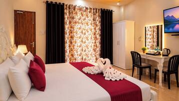 Quarto de hotel com cama, escrivaninha, cadeira, guarda-roupa e televisão.