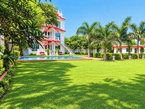 A large building with a swimming pool, surrounded by well-maintained grass and palm trees. - THE VRINDAVAN RESORT & BANQUET BY MTJ HOSPITALITY SERVICES LUCKNOW (Bakshi Ka Talab)