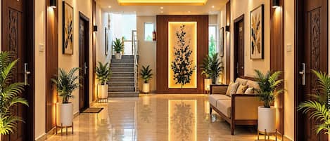 A hotel lobby with a polished marble floor, a central seating area with a sofa, and a staircase leading to upper floors.