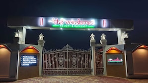 A gated entrance to a resort with a sign indicating amenities like party lawns, banquet hall, meeting halls, swimming pool, and rooms.
