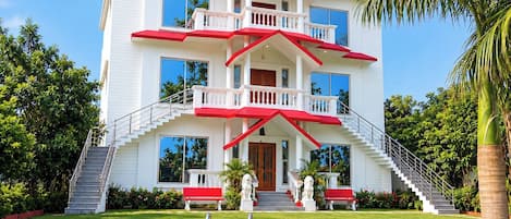 A multi-story building with a pool, stairs, and statues.