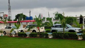 A residential area with parked cars, a garden with palm trees, and a building with water tanks on the roof.