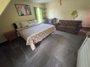 A bedroom with a bed, a sofa, a crib, and a radiator. - 4BR Salt Springs Retreat w/ Private Hot Tub (Salt Springs)
