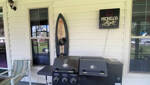 A grill set up on a porch with a sign for Michelob Light. - Spacious 4BR Ocala National Forest Home with Private Hot Tub Near Salt Springs — Sleeps 8 (Salt Springs)