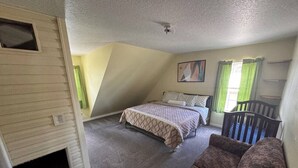 A bedroom with a bed, a sofa, a window with curtains, and a door. - Spacious 4BR Ocala National Forest Home with Private Hot Tub Near Salt Springs — Sleeps 8 (Salt Springs)